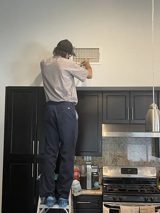 Technician inspecting an air vent during HVAC service in Oak Forest
